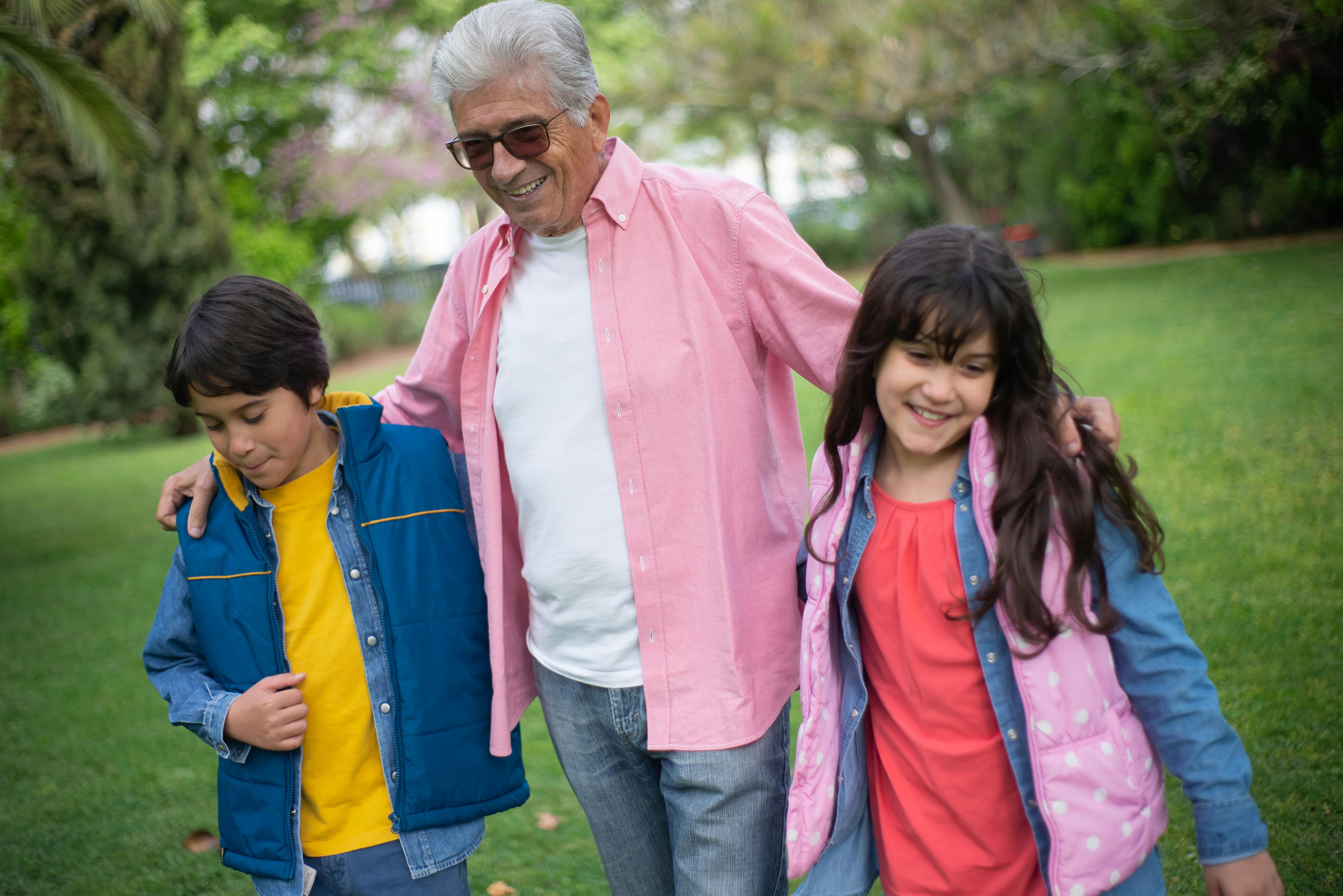 A grandfather walking with his grandchildren in a park